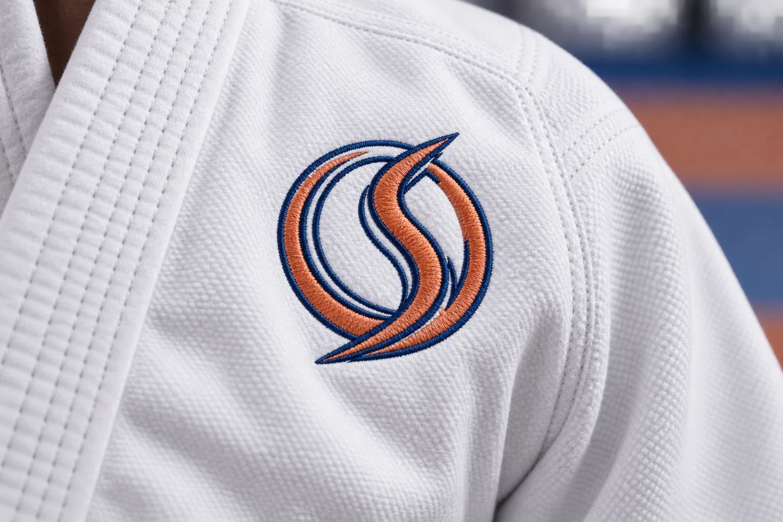Natural embroidered crest and academy patch detail on white gi fabric