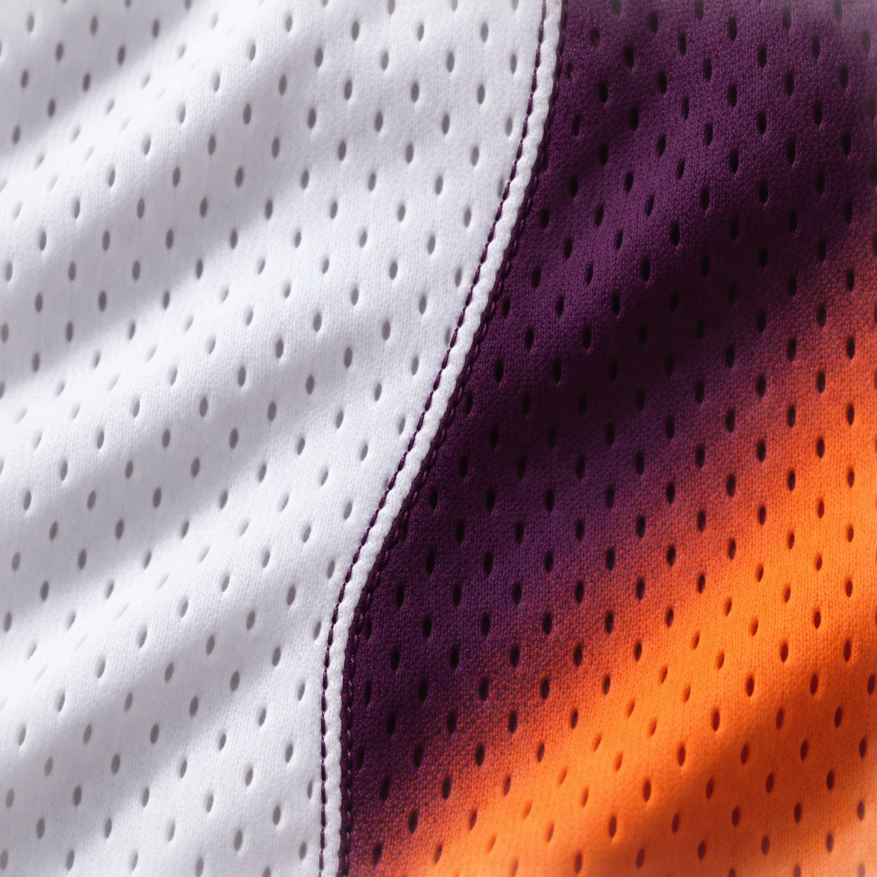 Close-up of white and violet perforated basketball knit meeting aubergine and orange sublimated mesh